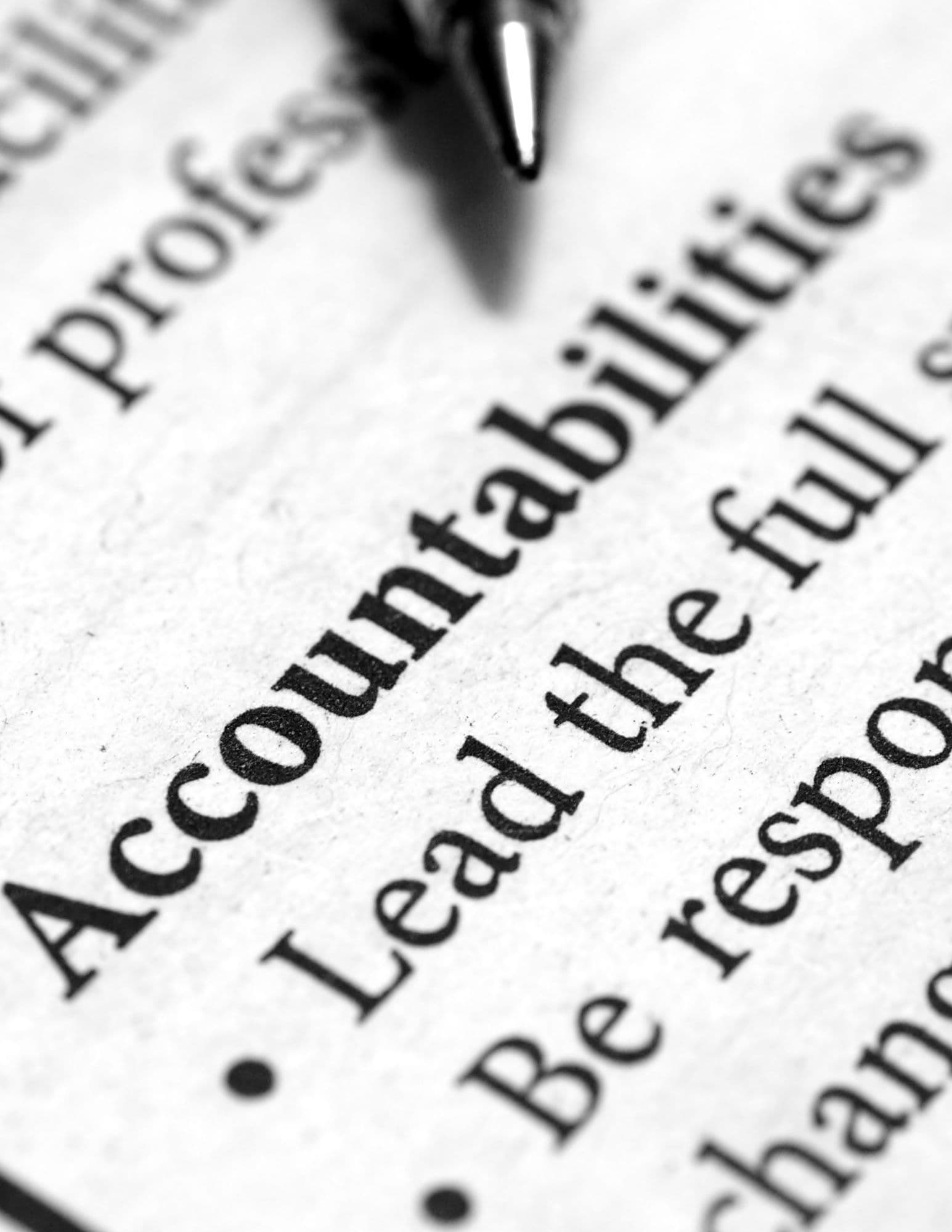 Close-up of the word Accountabilities on a printed document with a pen tip above.