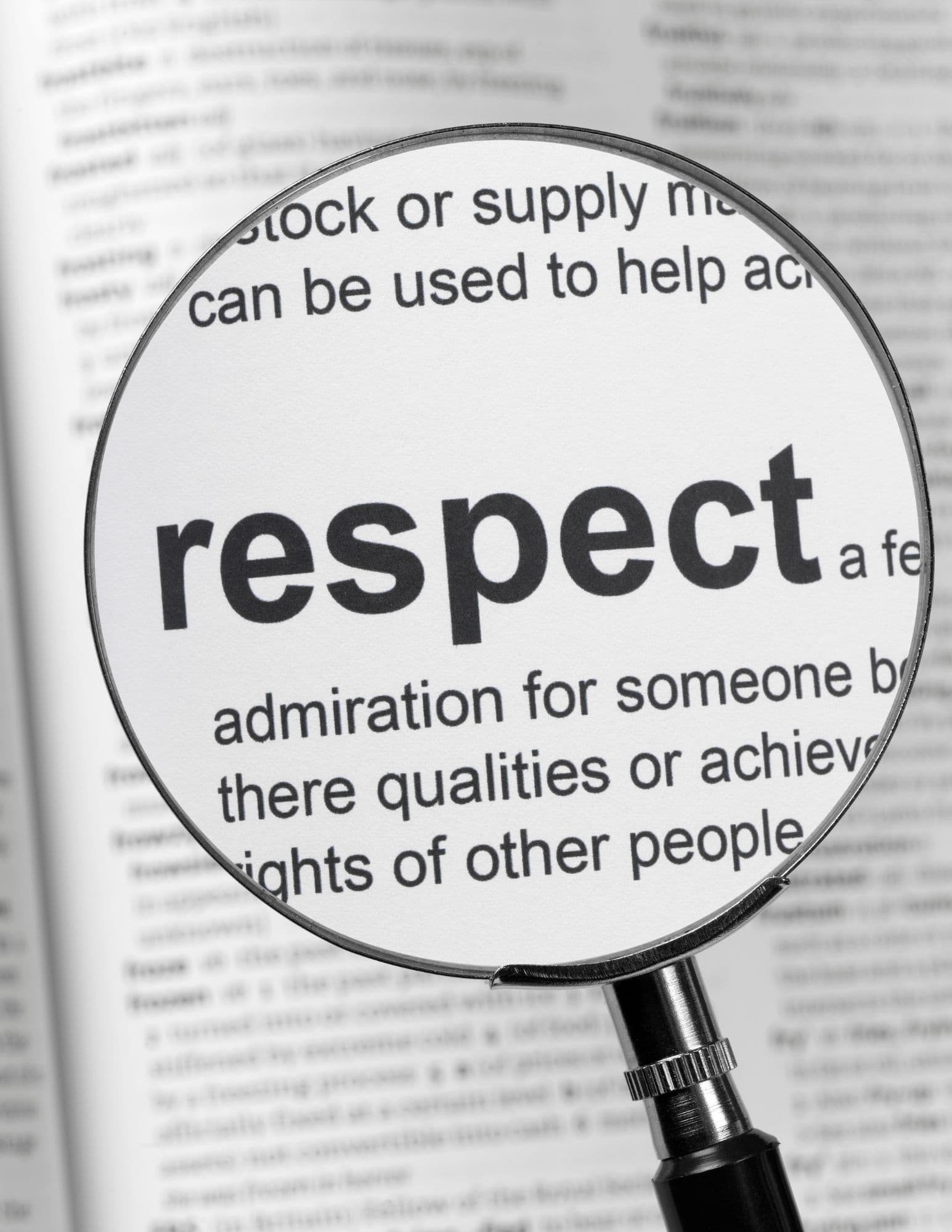 Magnifying glass focusing on the word respect and its definition on a dictionary page.